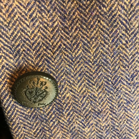Tweed Gehrock Damen lila mit Fischgrätmuster im Schnitt für Reitsport und Jagd. Ellenbogen Patches in orange. Detail Knopf.